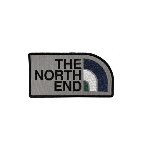 Embroidered patch with the words The North End and blue, white and green bars next to each word on a grey background.