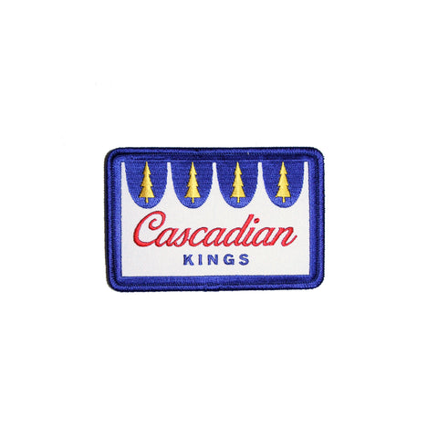 Embroidered wide rectangular patch in the style of the Hamm's Beer logo in white, with a blue outline with gold Douglas Firs and red text reading "Cascadian Kings"