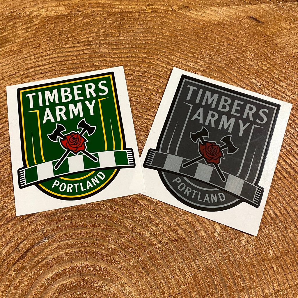Two vinyl cutout stickers with the New Timbers Army crest. One sticker is the crest in green and yellow, the other has the crest in greytones, and both have the classic Axe and Rose in red. 