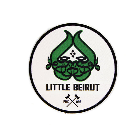 A white 5x5 patch with an embroidered design. The words "Little Beirut" above black crossed axes with PDX ORE on the sides. 