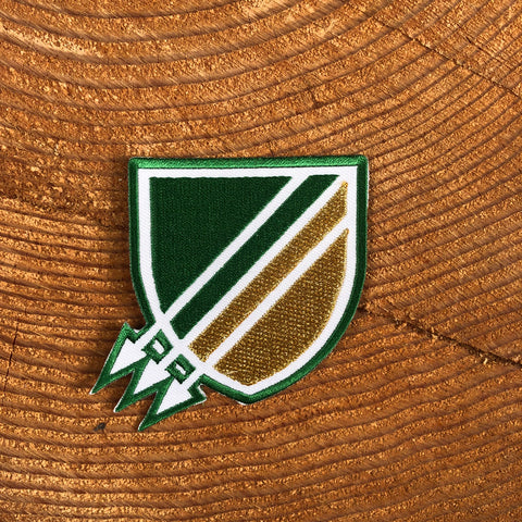 Three arrows pointing down and to the left on a shield shape on a background of green and gold.
