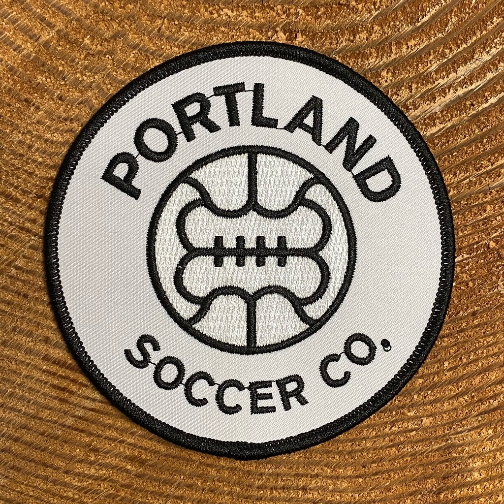 Round, white patch with an old-style soccer ball and the words "PORTLAND SOCCER CO" at the top and bottom